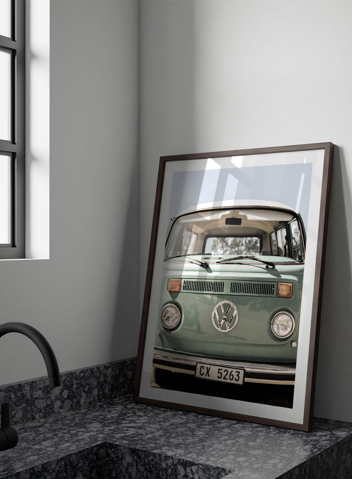 Front view of a vintage green Volkswagen van with clear sky background. Classic Design In Soft Green Tones by Shot by Clint car art print featuring a vintage Volkswagen camper van in soft sage green and warm sunlight.