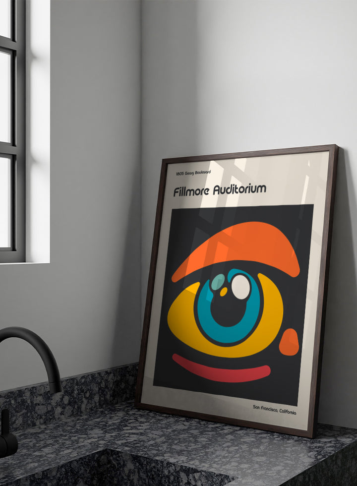 A poster-style graphic for the Fillmore Auditorium in San Francisco, California, featuring an abstract eye illustration in orange, yellow, blue, red, and white on a dark gray square, with cream margins and black text reading &
