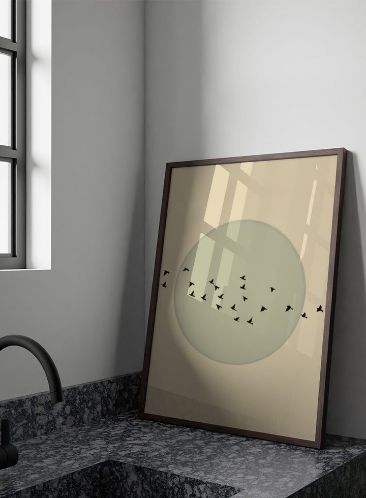Minimalist art print featuring a large muted sage green circle centered on a warm beige background, with small black bird silhouettes flying around it. Flock Against The Moon by The Art Concept is a minimalist bird art print featuring black birds in flight across a pale green moon and warm cream background.