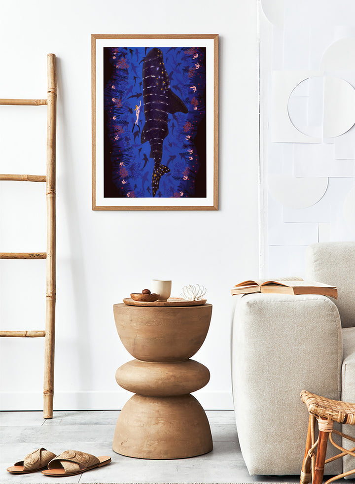 An illustrated art print featuring a large whale shark swimming through a deep blue ocean filled with smaller fish and coral. Diver and Whale Shark art print by Ceyda Alasar features a dramatic underwater view with a whale shark, diver, coral, and rich ocean blues.
