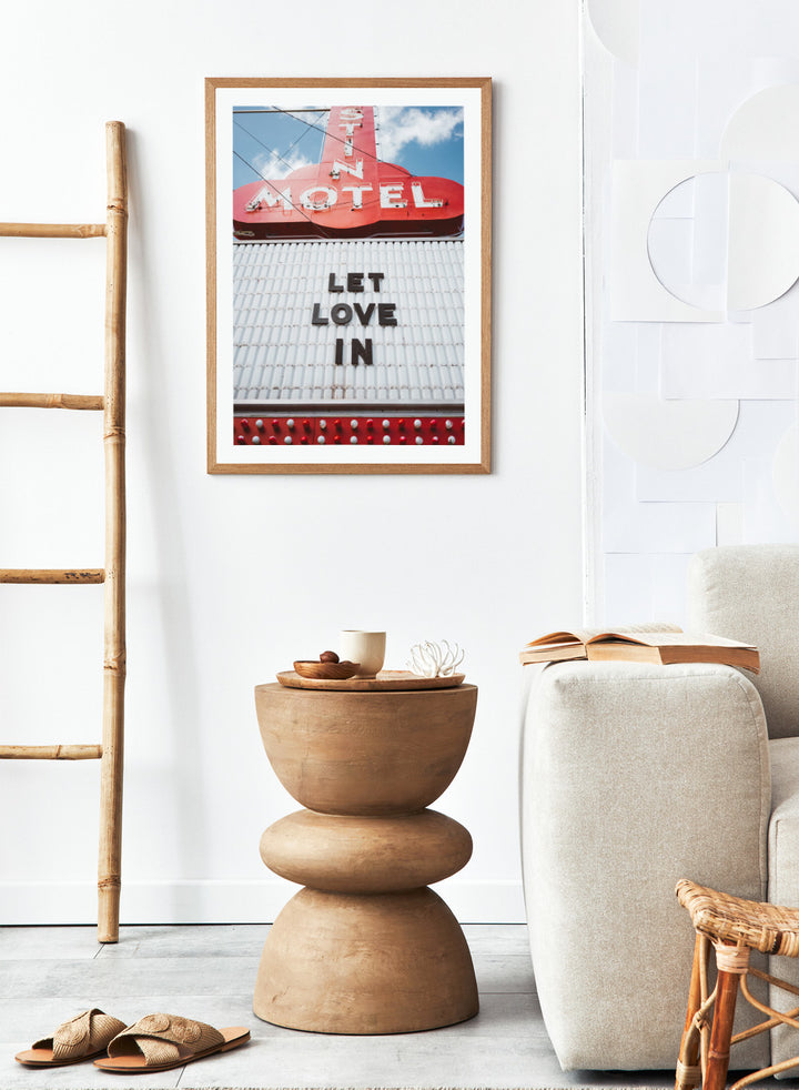 Vintage motel sign with 'Let Love In' message against a blue sky. Let Love In by Bethany Young features a vintage motel sign with red neon lettering against blue sky. Retro Americana photography wall art print.