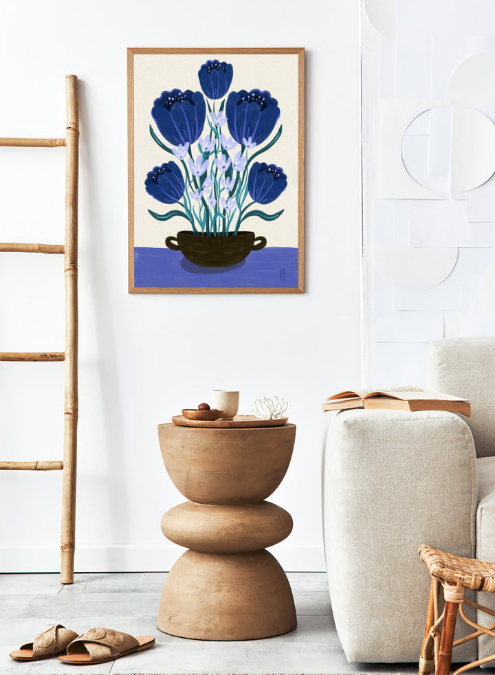 Artistic depiction of blue flowers in a black pot on a beige background. Blue Floral Arrangement by Dirkie Nell is a botanical floral art print featuring deep blue flowers, folk inspired illustration, modern wall art, and expressive hand painted details.