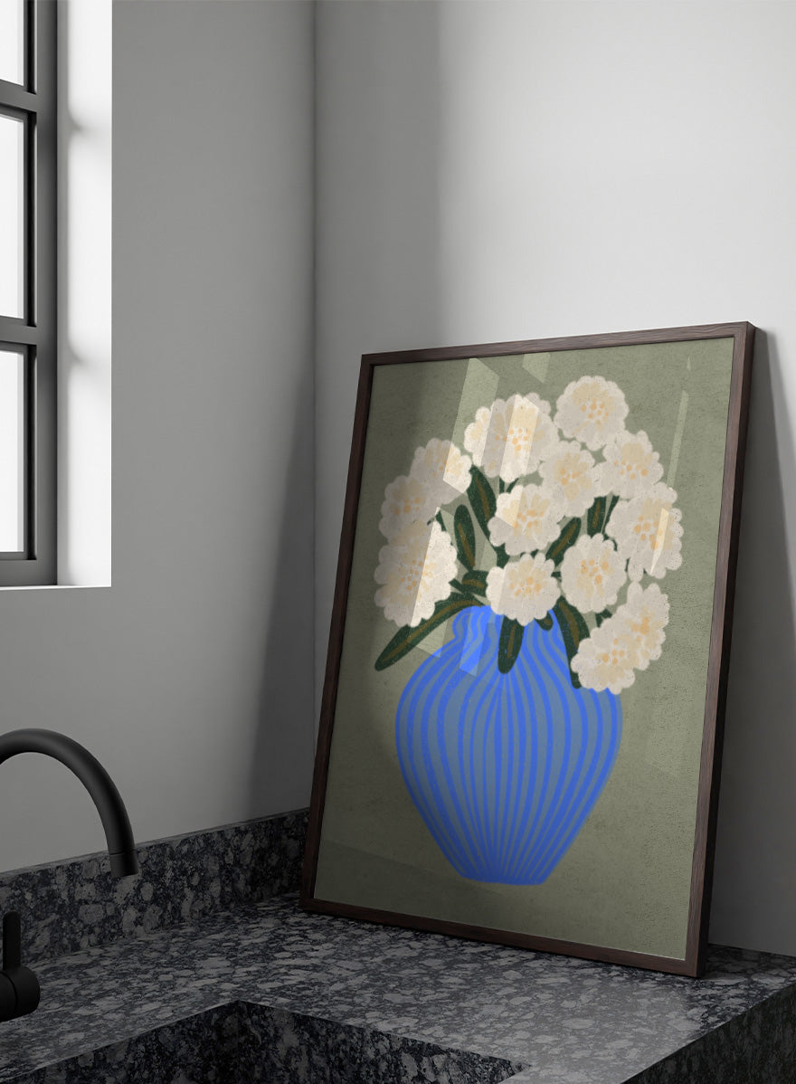 A stylized floral artwork showing a bouquet of off-white flowers with dark green leaves in a blue ribbed vase against a muted sage background. Shop White Blooms Blue Vase by Nikita Jariwala, a floral wall art print poster featuring white flowers in a striped blue vase with modern botanical style.