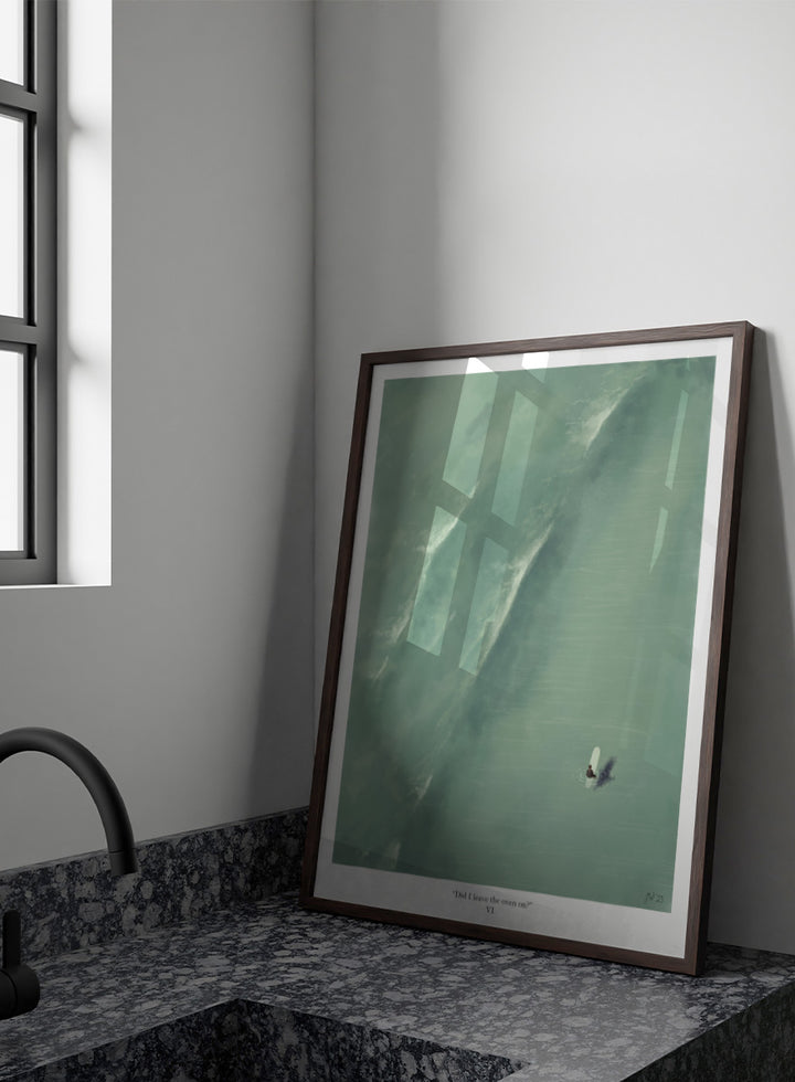 A framed art print featuring a minimalist aerial illustration of a surfer on a large wave, with the caption &