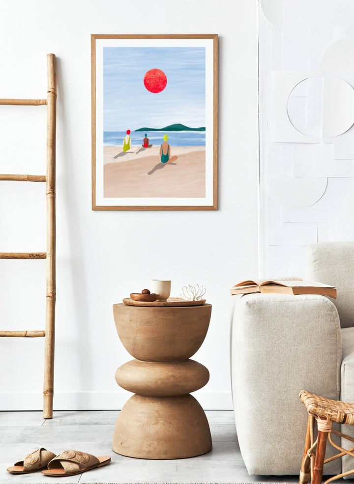 A minimalist art print depicting three figures meditating on a sandy beach under a large red sun. Red Sun Beach Serenity by Bea Müller premium fine art print featuring three figures on a beach beneath a bold red sun in a calm coastal setting.