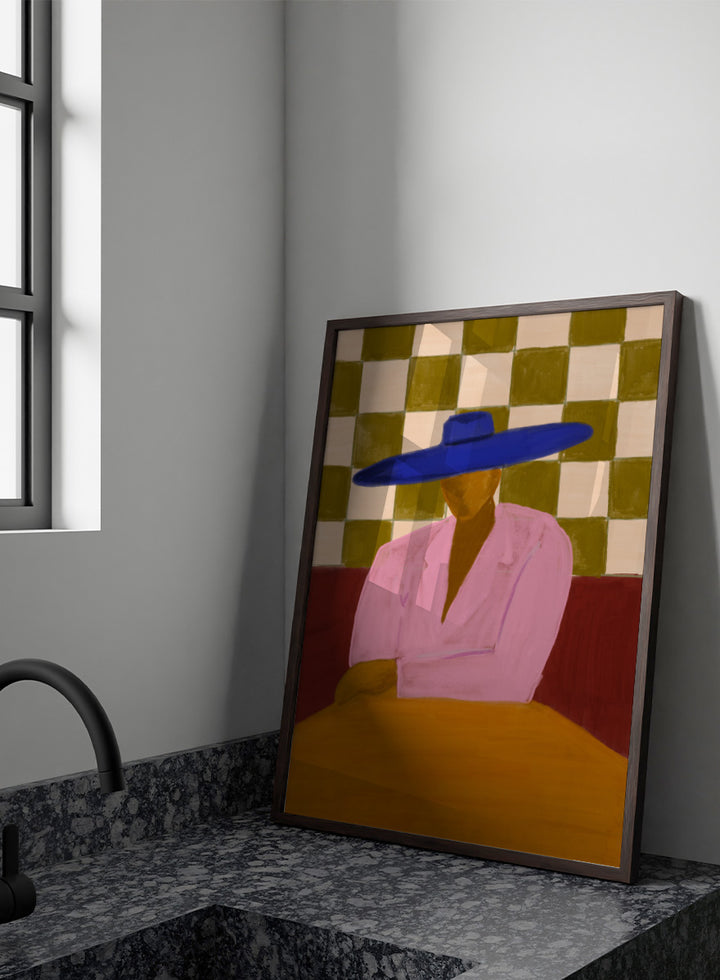 A stylized painting of a seated figure wearing a wide blue hat and pink top, with a red couch and a beige-and-olive checkered wall behind them. Blue Hat Chic by The Art Concept portrait art print featuring a cobalt blue hat, pink jacket, checkerboard backdrop, and bold modern color.