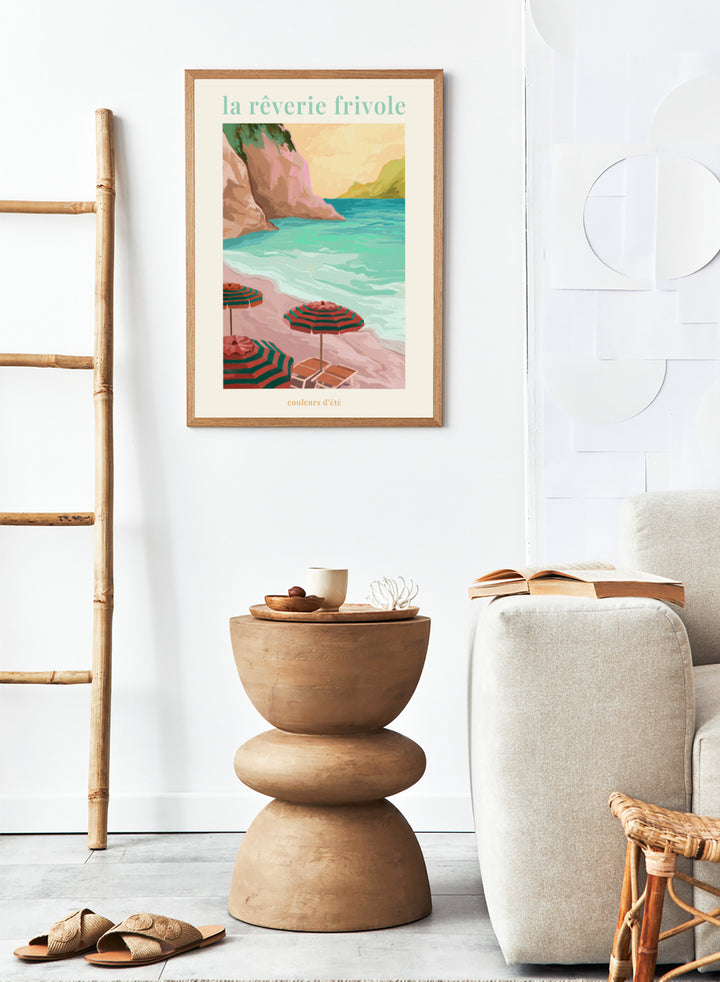 Beach scene with striped umbrellas and cliffs, featuring the text 'la reverie frivole'. La Rêverie Frivole Beach by Goed Blauw is a coastal art print and wall poster featuring striped umbrellas, turquoise water, and a warm seaside landscape.