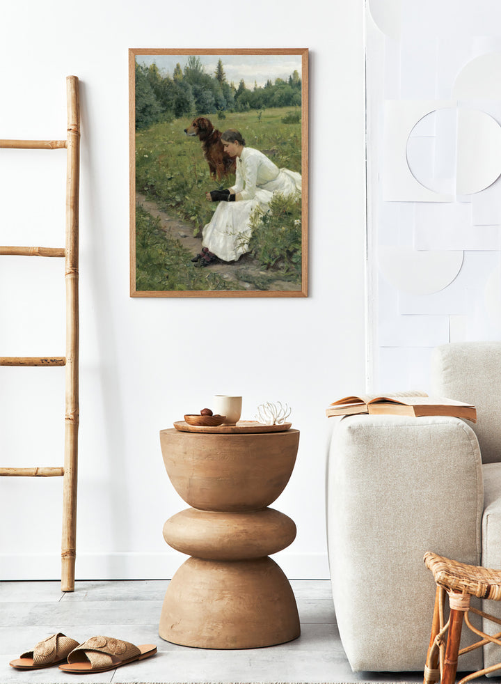 Idyll by Gerhard Munthe is a vintage Norwegian landscape print featuring a woman in a white dress resting with her dog in a green summer meadow.
