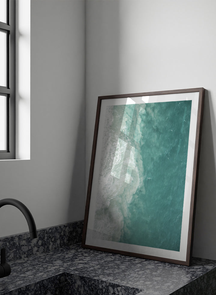 A framed aerial photograph of ocean waves, showing white foam breaking into turquoise and teal water. Ocean’s Edge by Shot by Clint aerial ocean photography print featuring turquoise water, white surf, and layered coastal movement.