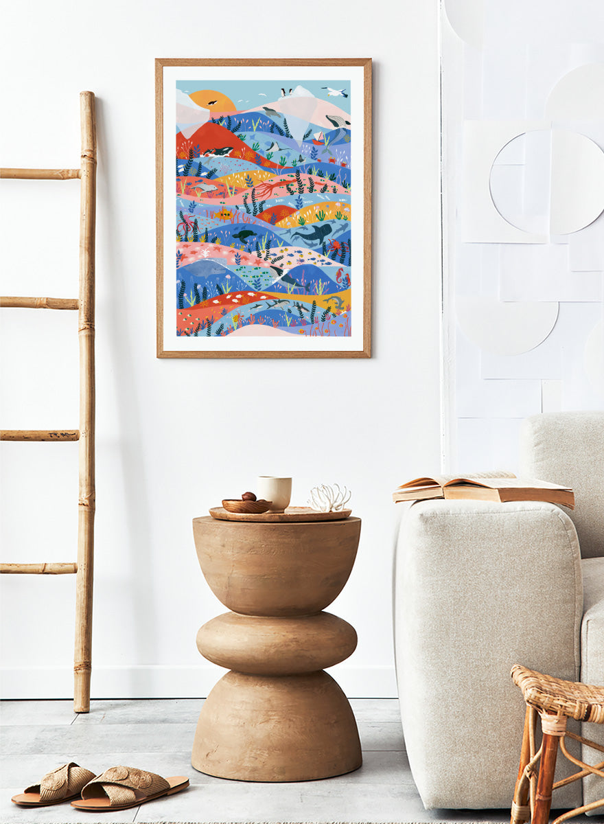 A colorful illustrated art print featuring stylized mountains, sea life, and coastal scenery in layered wavy bands of blue, pink, orange, yellow, and green. Vibrant Ocean Life by Ceyda Alasar ocean art print featuring whales, sharks, rays, turtles, coral reefs, sea plants, and colorful marine life.