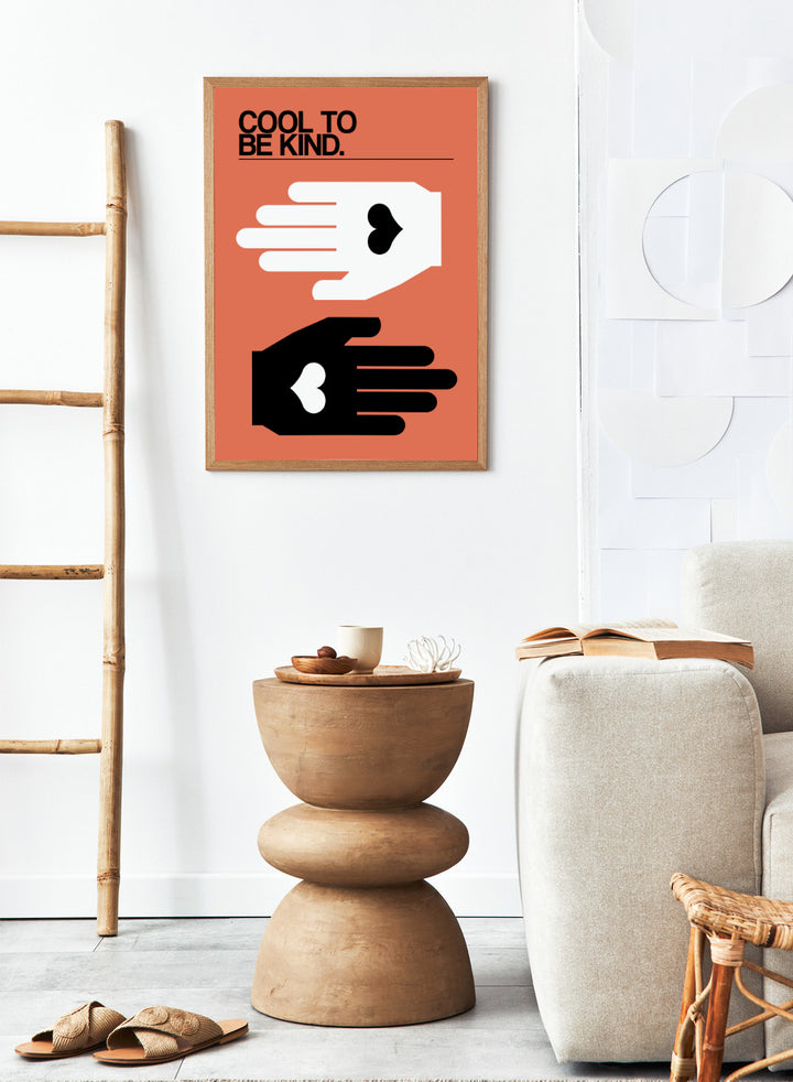Poster with two hands reaching towards each other, one white and one black, on an orange background with 'Cool to be kind' text. Cool To Be Kind by Frances Collett is a modern kindness art print featuring two graphic hands with heart symbols. Officially licensed contemporary wall poster with optional framing.