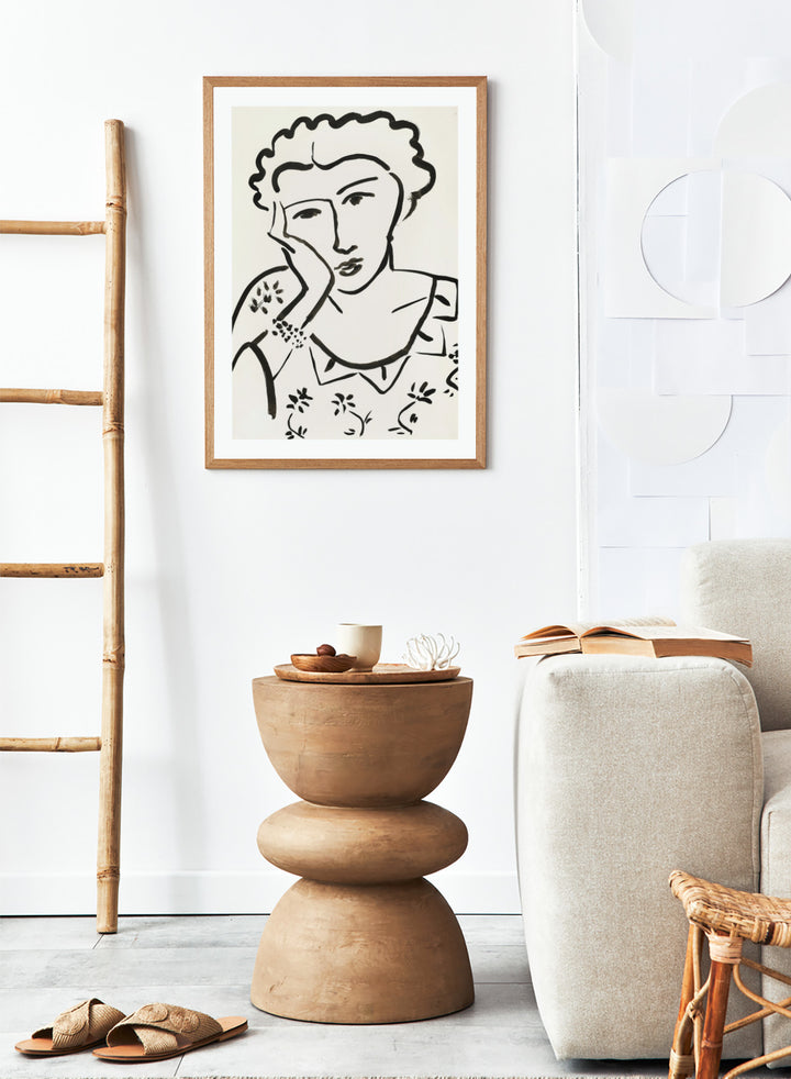 Black line art of a woman with floral patterns on a white background. Jeune Fille Accoudée by Henri Matisse is a minimalist portrait art print featuring expressive black linework, floral detailing, and refined French modernist design.