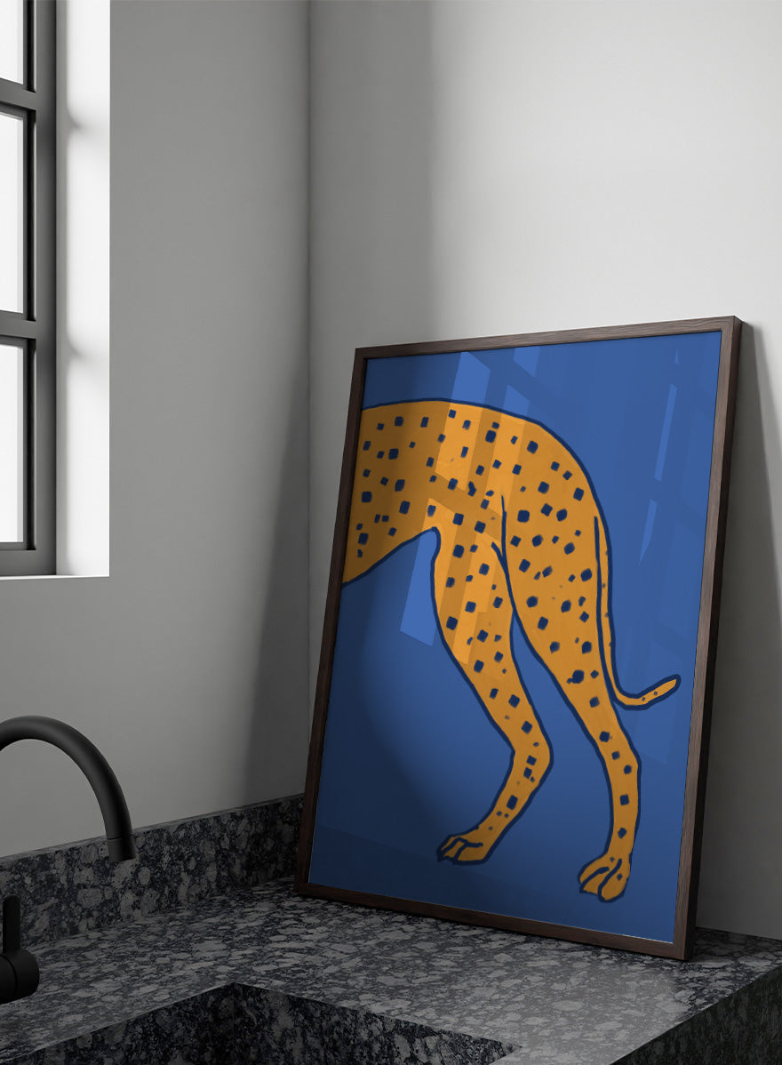 A stylized illustration of a spotted big cat, cropped to show the torso and hind legs, in orange with dark blue spots on a solid blue background. Spotted Cheetah on Blue by The Art Concept animal art print featuring a cropped golden cheetah with deep blue spots against a bold blue background.