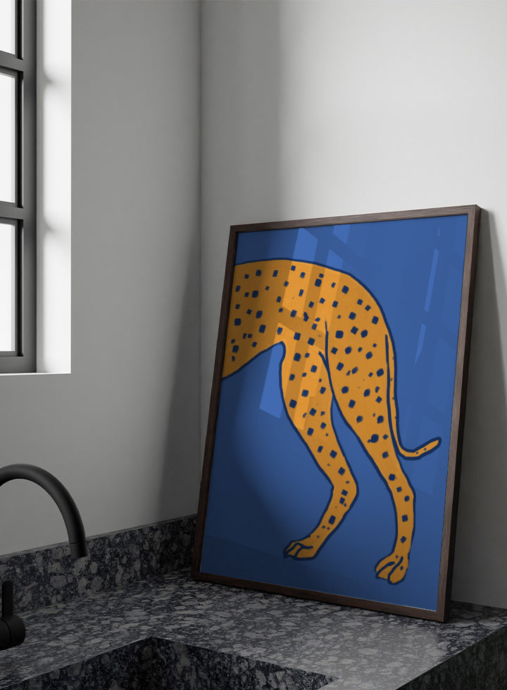 A stylized illustration of a spotted big cat, cropped to show the torso and hind legs, in orange with dark blue spots on a solid blue background. Spotted Cheetah on Blue by The Art Concept animal art print featuring a cropped golden cheetah with deep blue spots against a bold blue background.