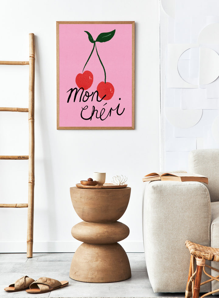 Two red cherries with green stems on a pink background and 'mon chéri' text. Mon Chéri by Dirkie Nell is a cherry typography art print featuring bold red fruit and playful lettering. A colorful love-inspired wall poster.