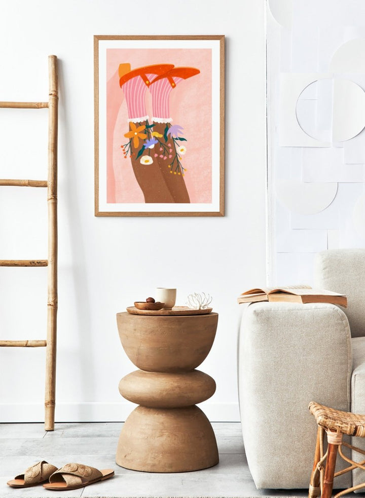 A stylized art print featuring a pair of legs wearing pink striped socks with white ruffles, decorated with colorful wildflowers, and topped with orange high-heeled shoes, set against a textured pink background. Happy Feet and Flowers by Bea Müller premium framed fine art print featuring red Mary Janes, striped socks, and colorful flowers on a soft pink background.