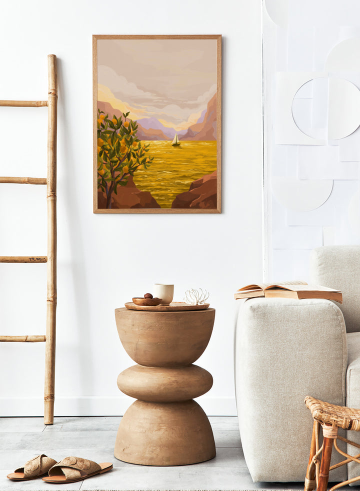 Sailing boat on a yellow sea with mountains and lemon tree in the foreground. Golden Sunset by Goed Blauw is a coastal art print and wall poster featuring a sailboat on a glowing ocean with cliffs and an orange tree.