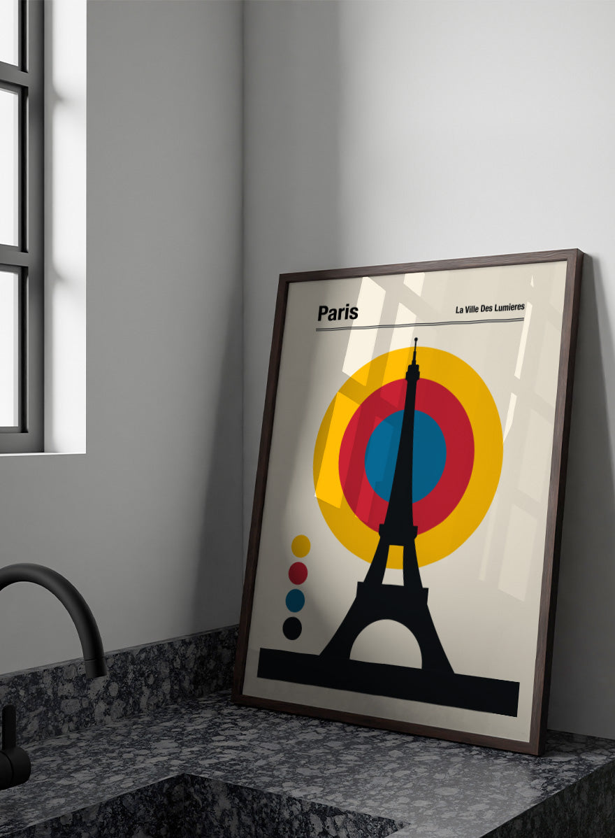 A minimalist Paris poster featuring a black Eiffel Tower silhouette in front of concentric yellow, red, and blue circles on a cream background, with the text &