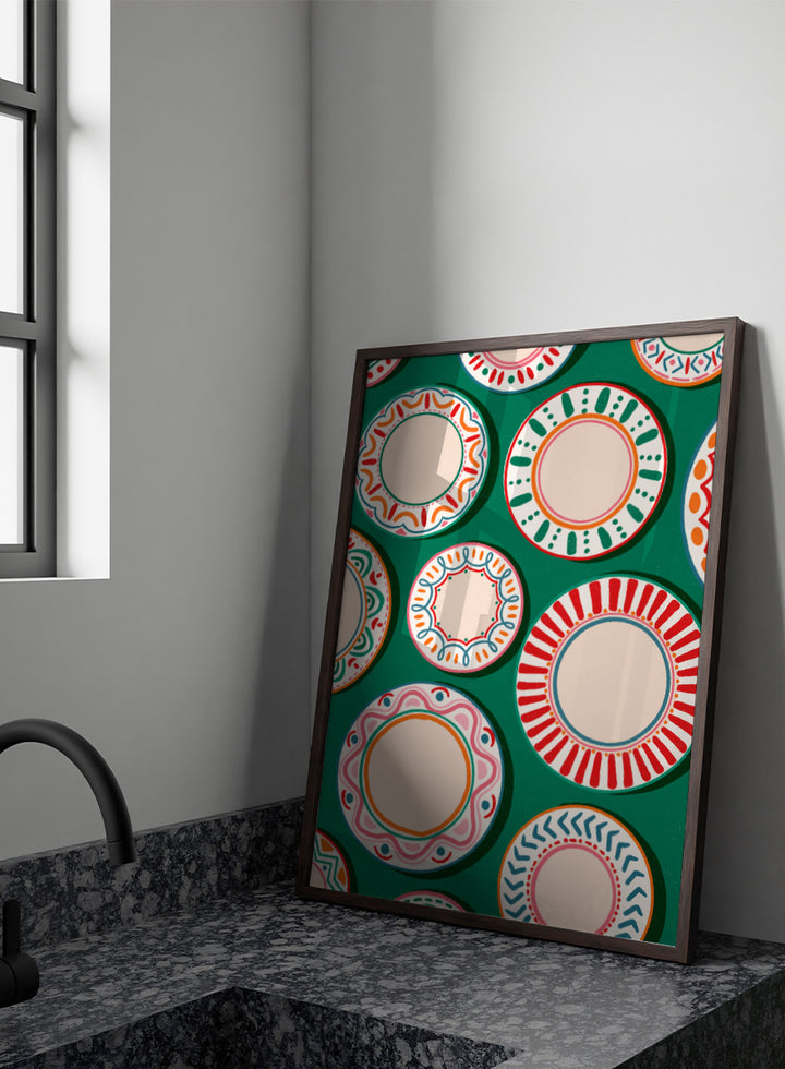 A flat-lay pattern of colorful decorative plates on a dark green background, featuring a variety of circular designs in red, orange, pink, blue, and cream. Shop Colorful Patterned Plates by Nidhi Kachhadiya, a playful kitchen wall art print featuring decorative plates, folk-inspired patterns, and bold green, red, and pink tones.