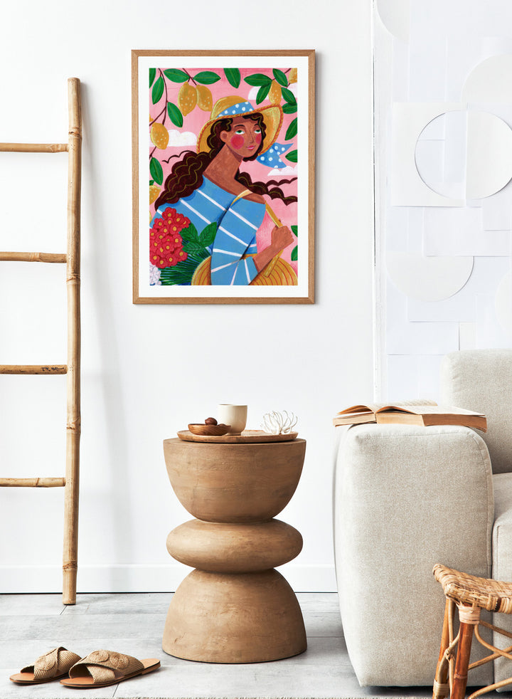 Colorful artwork of a woman with braided hair, wearing a straw hat and striped shirt, against a pink background with lemons and flowers. Lemon Tree Summer by Caroline Bonne Müller is a fine art print and wall poster of a woman under lemon branches with flowers in a bright modern aesthetic.