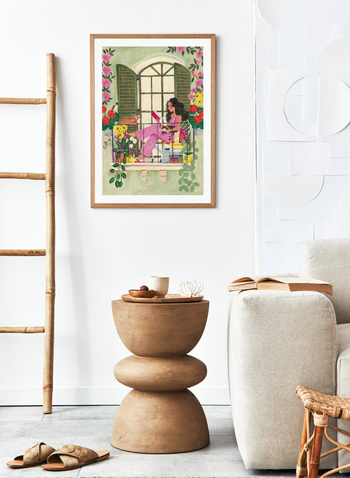 Illustration of a woman reading a book on a balcony with flowers and plants. Balcony Reading With Cats by Caroline Bonne Müller is a fine art print and wall poster of a woman reading on a balcony with cats and flowers in a modern style.