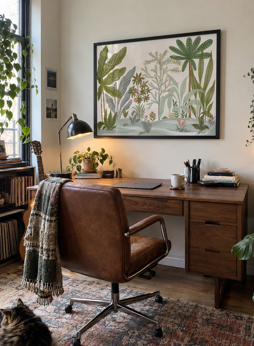 A framed botanical art print featuring a collection of tropical and jungle plants in muted green, gray, and soft pink tones on a cream background. Shop Lush Tropical Jungle by Nikita Jariwala, a tropical botanical wall art print poster with jungle plants, palm leaves, layered foliage, and green tones.