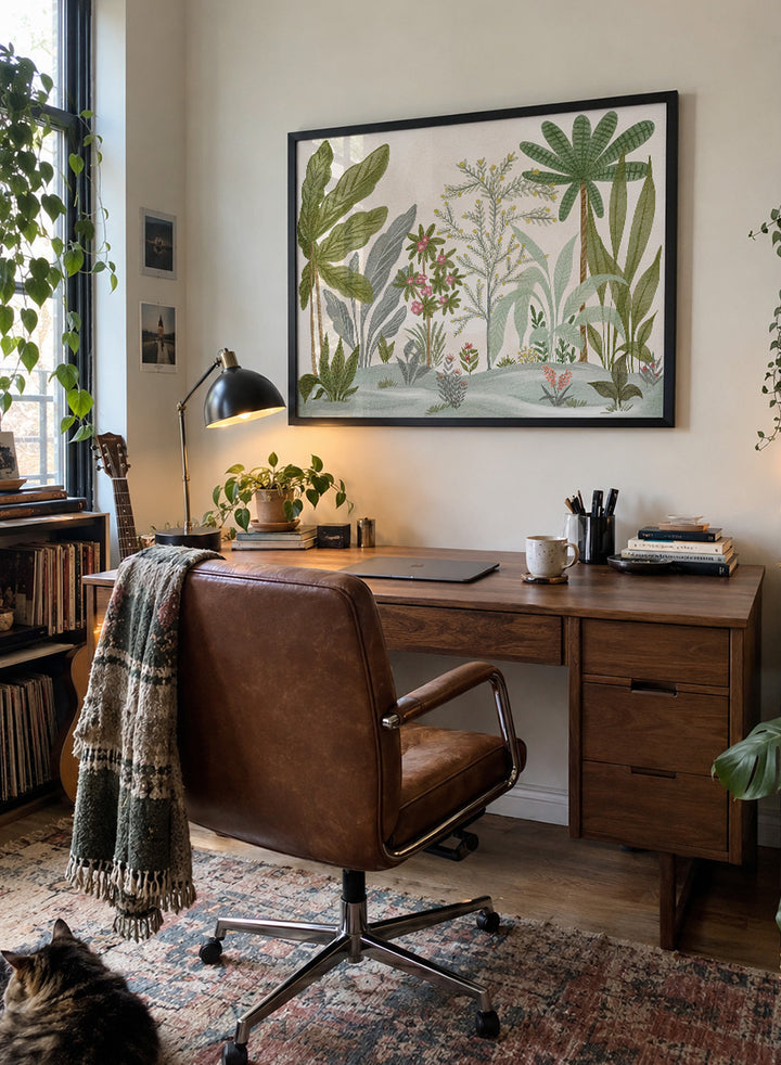 A framed botanical art print featuring a collection of tropical and jungle plants in muted green, gray, and soft pink tones on a cream background. Shop Lush Tropical Jungle by Nikita Jariwala, a tropical botanical wall art print poster with jungle plants, palm leaves, layered foliage, and green tones.