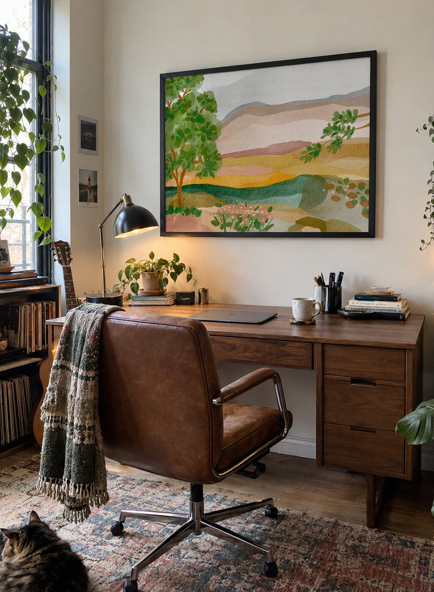 A framed landscape art print featuring a stylized watercolor scene with green trees, layered hills, and a river. Shop Peaceful Valley View by Nikita Jariwala, a serene landscape wall art print poster featuring rolling hills, distant mountains, wildflowers, and soft green tones.