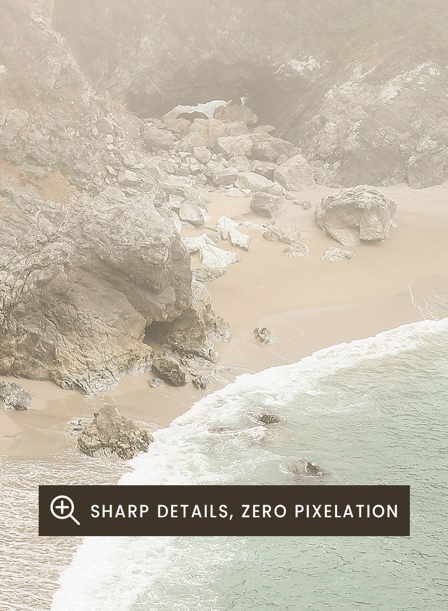 A framed photographic print of a misty coastal beach scene with a small waterfall, sandy shore, and pale blue-green ocean waves. Misty Coastal Haven by Shot by Clint coastal photography print featuring a secluded cove, rocky cliffs, pale turquoise water, and a soft veil of mist.