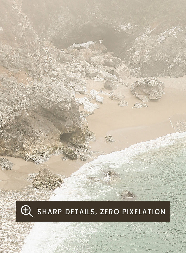 A framed photographic print of a misty coastal beach scene with a small waterfall, sandy shore, and pale blue-green ocean waves. Misty Coastal Haven by Shot by Clint coastal photography print featuring a secluded cove, rocky cliffs, pale turquoise water, and a soft veil of mist.