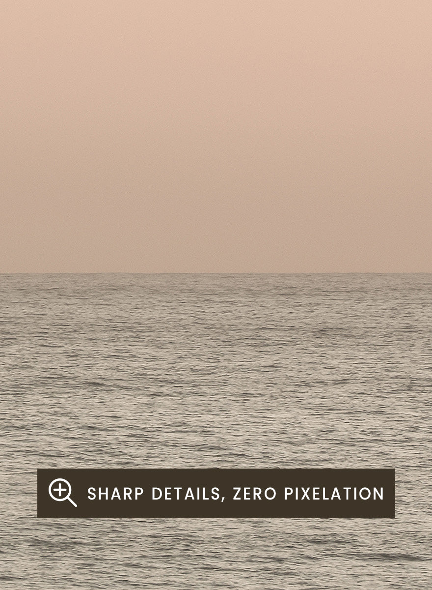 A minimalist framed art print depicting a calm seascape at dusk or dawn, with a soft peach and beige sky meeting a muted gray-blue ocean horizon. Serene Horizons by Shot by Clint features a soft peach sky and calm ocean horizon in a minimal coastal photograph with airy neutral tones.