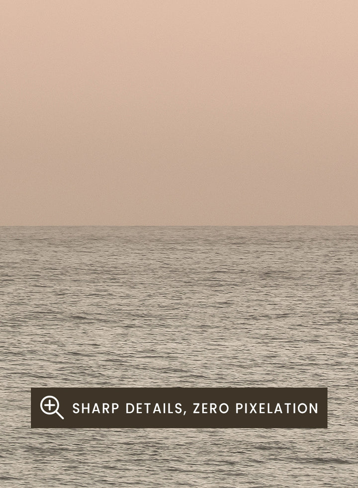 A minimalist framed art print depicting a calm seascape at dusk or dawn, with a soft peach and beige sky meeting a muted gray-blue ocean horizon. Serene Horizons by Shot by Clint features a soft peach sky and calm ocean horizon in a minimal coastal photograph with airy neutral tones.