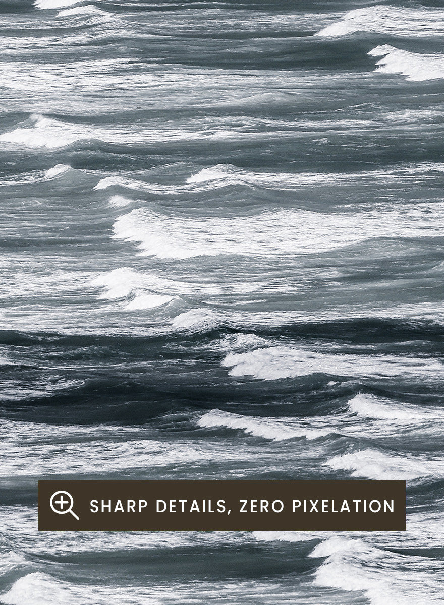 A framed black and white photographic print depicting a close-up view of ocean waves with white foam crests against dark water. Waves in Rhythm by Shot by Clint ocean photography print featuring layered blue-grey waves, white foam, and powerful natural movement across the sea.