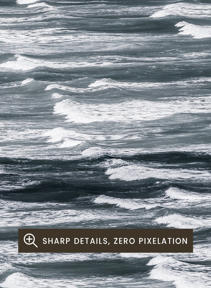 A framed black and white photographic print depicting a close-up view of ocean waves with white foam crests against dark water. Waves in Rhythm by Shot by Clint ocean photography print featuring layered blue-grey waves, white foam, and powerful natural movement across the sea.