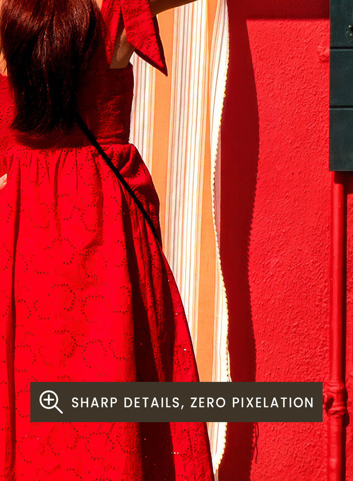 Woman in a red dress and white hat standing in front of a red wall with green shutters. Red Art Print by Anette Ohlendorf featuring a woman in a red dress standing against a red building. Officially licensed travel photography with strong color and symmetry.