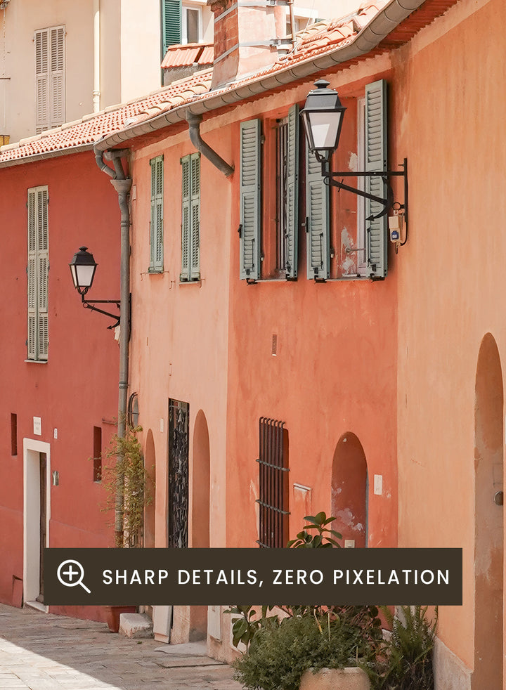 Tiled street with colorful buildings and greenery under a clear blue sky. Colorful Old Town Street by Henrike Schenk is a European travel photography print featuring Mediterranean architecture, pastel buildings, and street wall art.