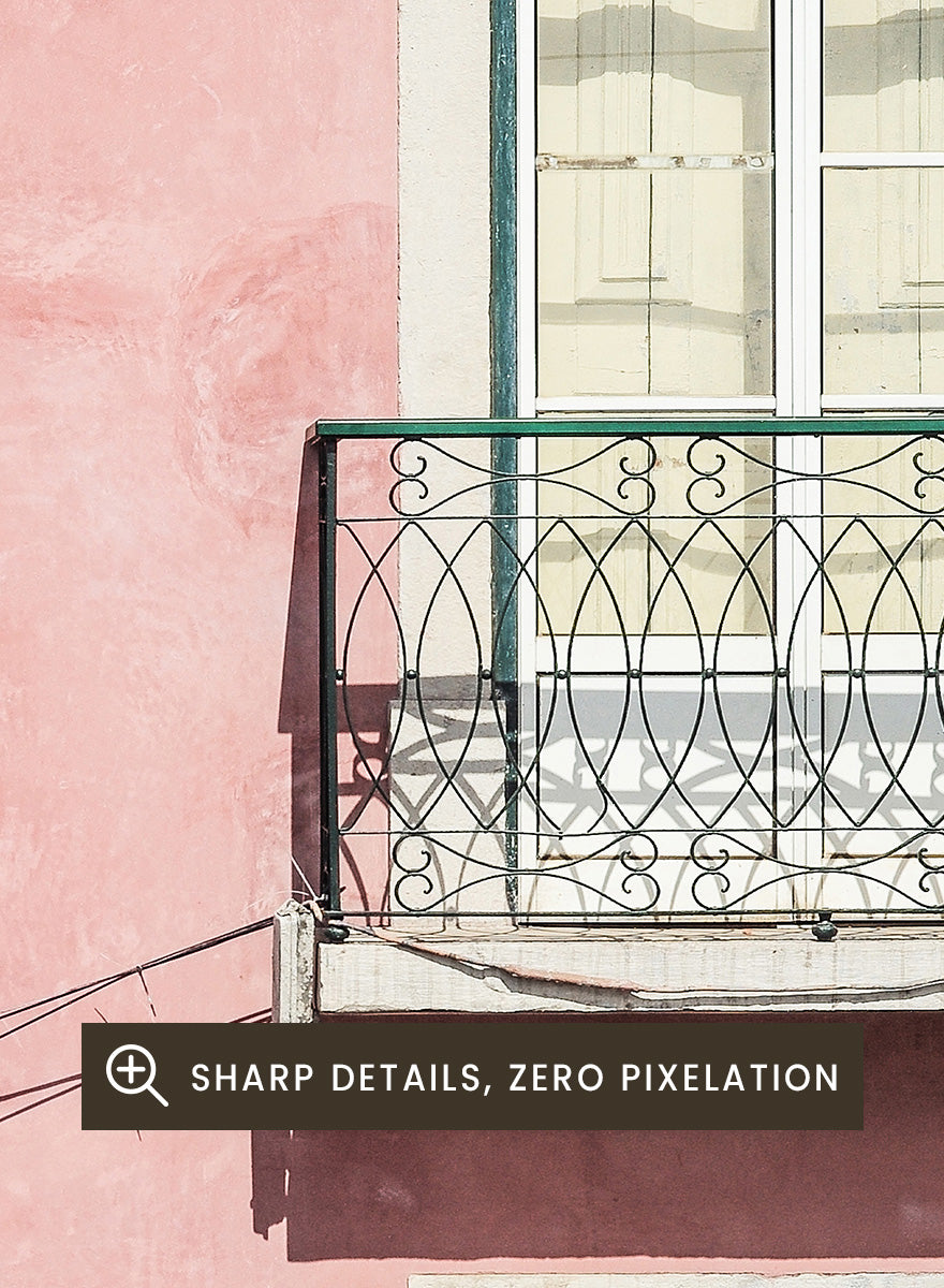A framed art print featuring a photograph of a pink building facade with green doors, white-framed windows, and a small black metal balcony. Pink Façade Harmony by Shot by Clint architectural photography print featuring a pink exterior, green doors, white windows, and an iron balcony.