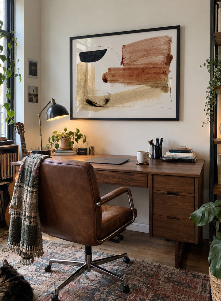 Abstract framed wall art featuring broad brushstrokes in terracotta, beige, black, and brown on a cream background. Shop Cooking by Dan Hobday, a warm abstract art print featuring rust brown, black, and sandy neutral forms with loose lines and layered brush texture.