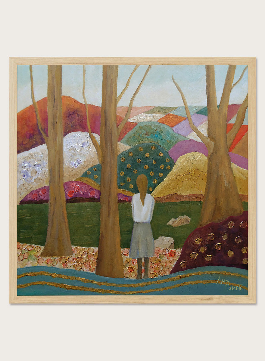 A framed landscape painting featuring a woman standing among tall trees, looking over a patchwork field of hills in earthy tones of green, purple, orange, and beige. Shop Woman Among Vibrant Hills by Angeles M. Pomata, a colorful landscape and portrait art print featuring a woman, rolling hills, trees, and earthy tones.