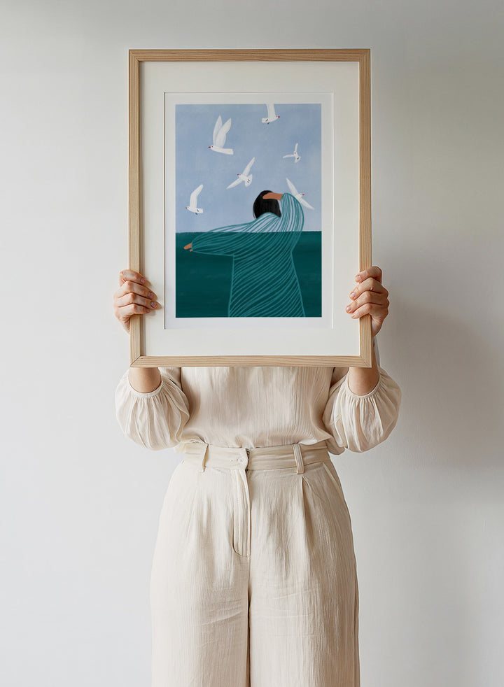 Seaside Serenity by Bea Müller is an officially licensed art print featuring a calm seaside figure and flying birds. Available as fine art print or framed with real wood frames.
