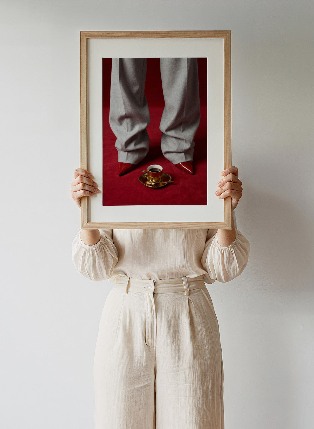 White pants with red shoes on a red carpet, featuring a gold cup and saucer with coffee. Red Shoes and Coffee by Andreas Magnusson is a fashion photography art print featuring red heels and espresso. Officially licensed modern wall poster.