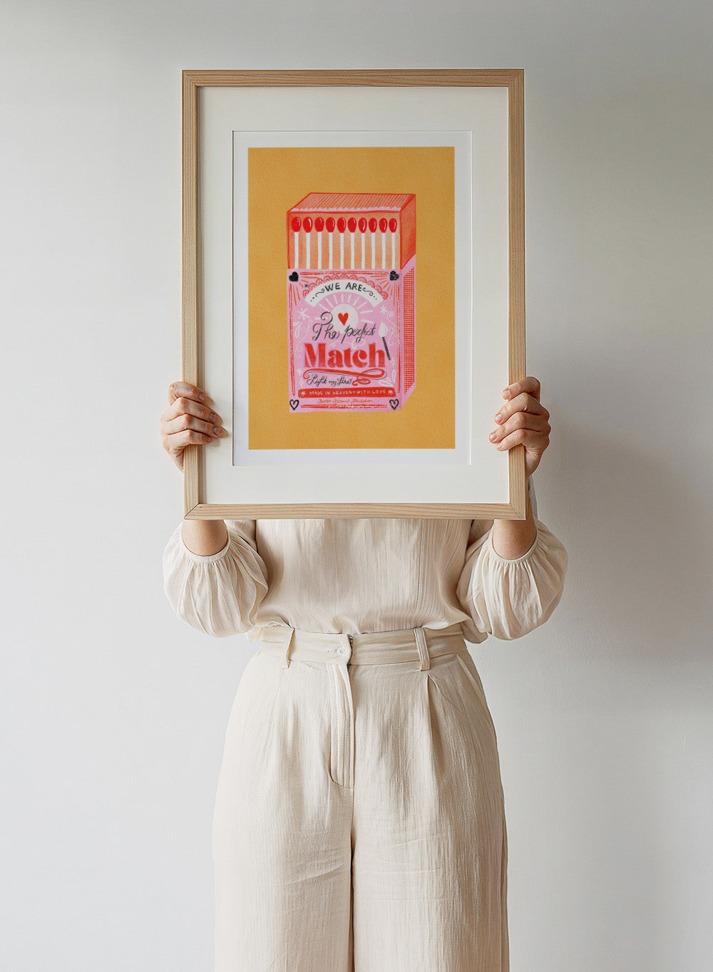 Illustration of a matchbox with 'We are the perfect match' text on a yellow background. Match Box, The Perfect Match by Baroo Bloom is a playful love-themed art print featuring a pink illustrated matchbox. Officially licensed wall poster with optional framing.