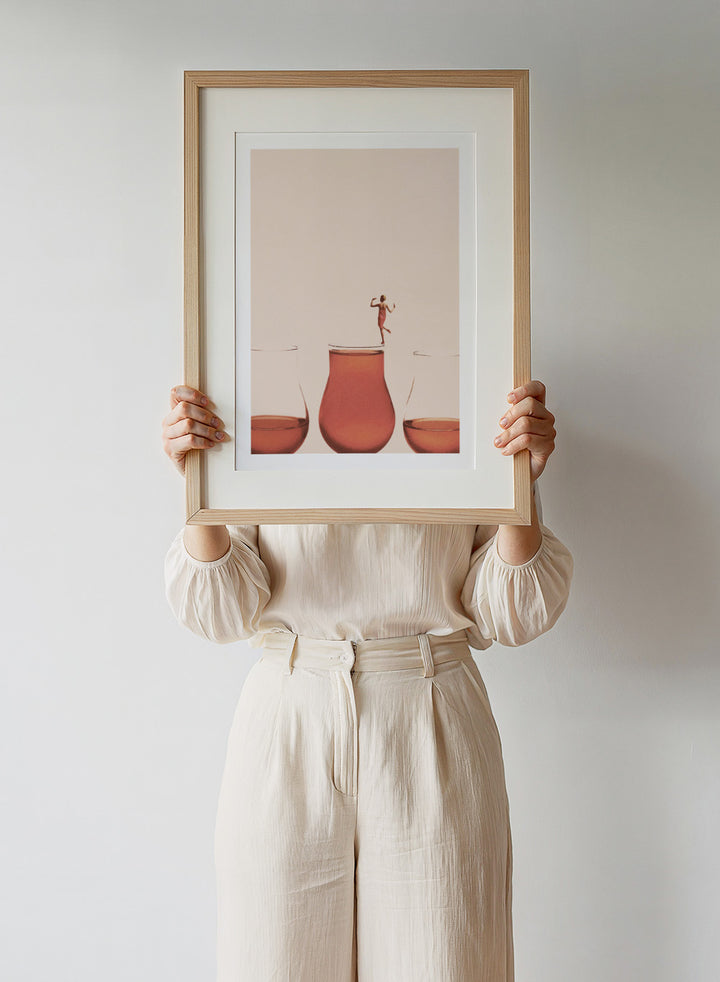 I Prefer the Full One by Maarten Léon collage art print featuring a woman standing on a full glass. Premium fine art print with real wood framing.