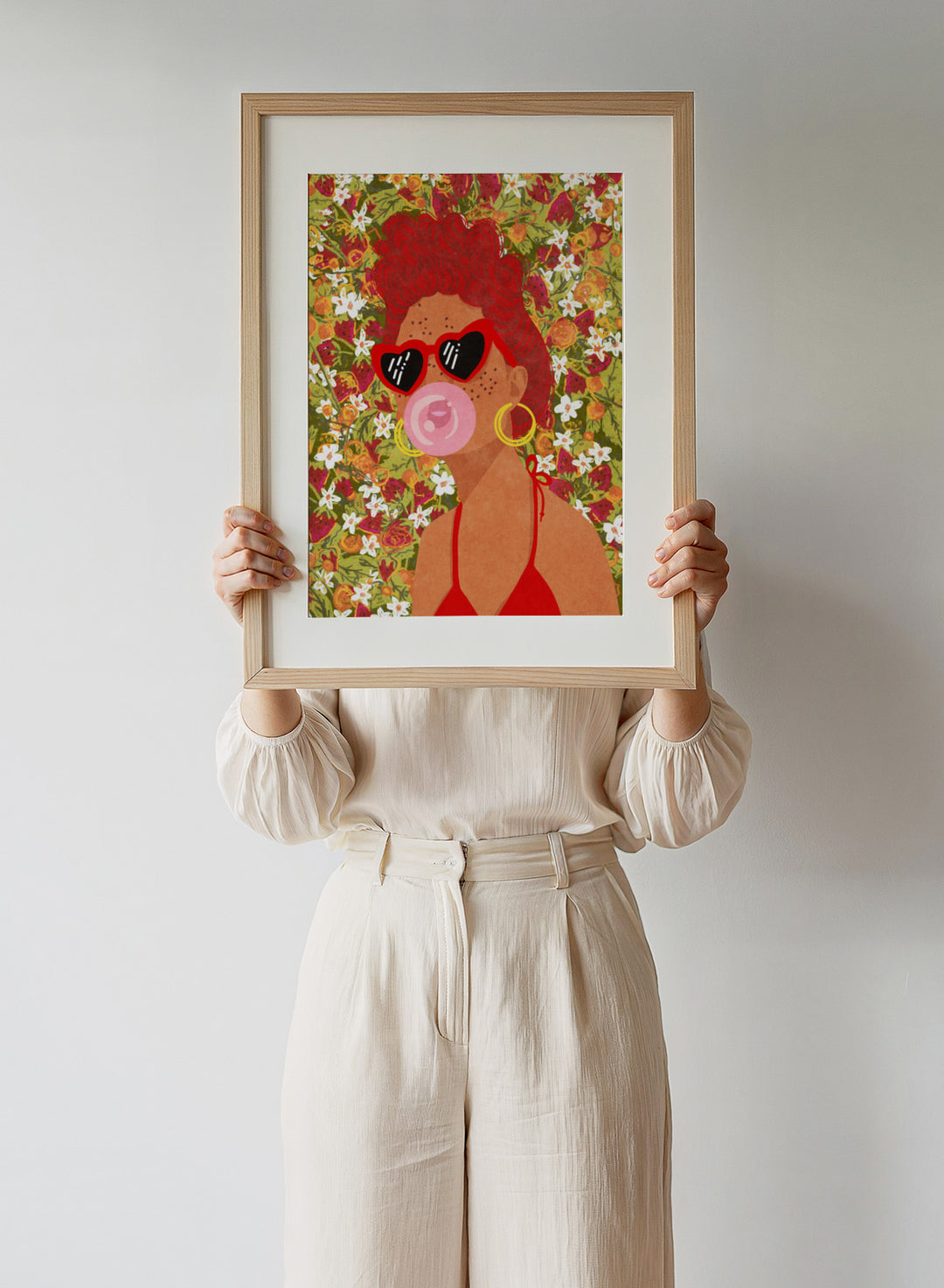 Illustration of a woman with red hair, sunglasses, and a pink bubble gum against a floral background. Strawberry Lady by Raissa Oltmanns fine art print featuring bold female portrait with strawberry background, modern colorful wall decor poster.
