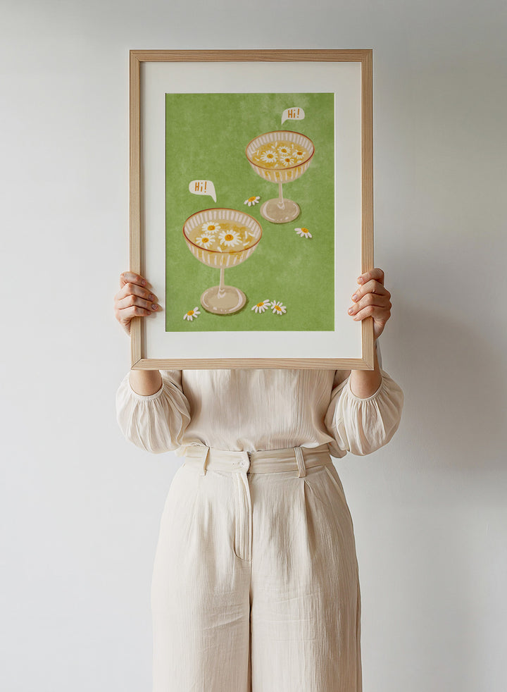 Illustration of two cocktail glasses with daisies on a green background. Hi by Raissa Oltmanns is a modern cocktail art print featuring smiling daisy drinks in playful contemporary wall poster style.