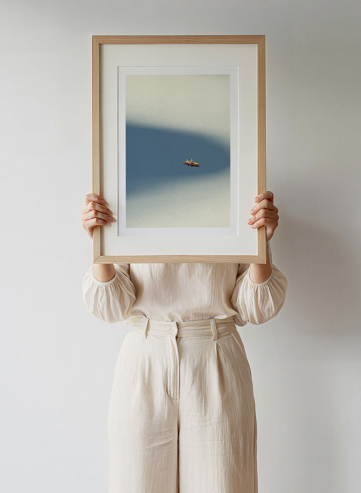 Happy Memories by Maarten Léon is an officially licensed art print featuring a minimalist boat scene with soft blue tones and open water. Available as a premium fine art print with optional real wood framing.