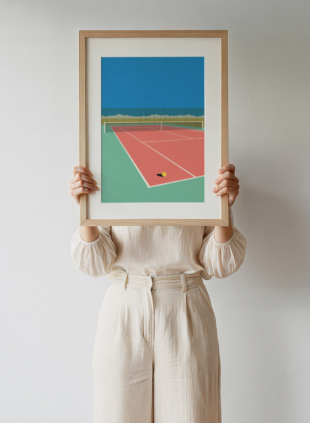 Illustration of a tennis court with a ball on the ground and mountains in the background. Tennis Court in the Desert by Rosi Feist is a modern minimalist fine art print of a pink tennis court in a surreal desert landscape. Officially licensed wall poster with optional artisan framing.