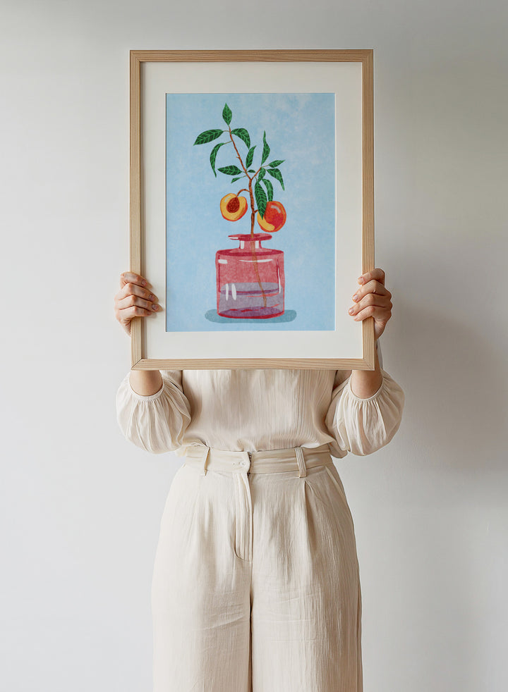 Illustration of a peach tree in a glass vase against a light blue background. Peach Tree in Vase by Raissa Oltmanns is a modern peach still life art print with fruit branch and kitchen wall poster design.