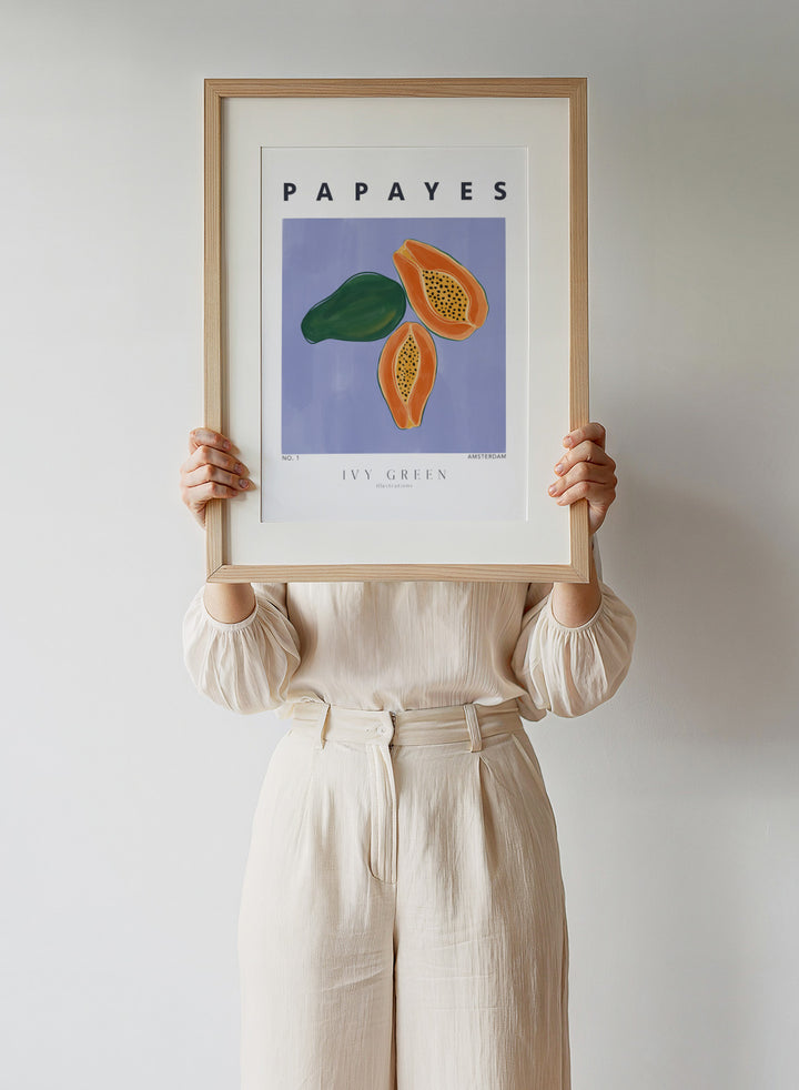 Illustration of papayas and a leaf on a blue background with 'Papayes' text at the top. Papayes by Ivy Green fruit art print featuring papaya illustration, modern food poster design, and colorful contemporary kitchen wall art.