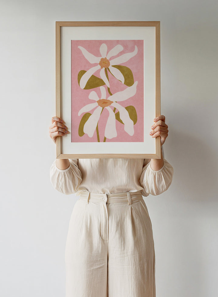 Two white flowers with green stems on a pink background. Abstract Flowers I by Raissa Oltmanns is a modern floral art print featuring white blooms on pink in contemporary botanical wall poster style.